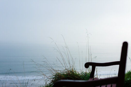 Dark wooden bench overlooking the sea against a grey misty foggy sky