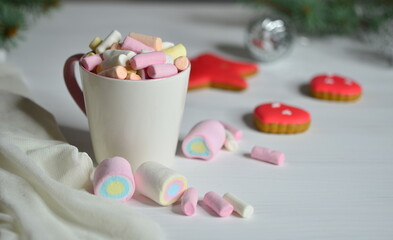 Fototapeta na wymiar Cup with marshmallows and gingerbread. Christmas balls are blurred.