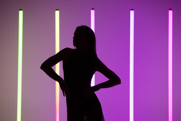 Silhouette of a sexy attractive young woman posing at purple studio background with neon lamps. Close up.