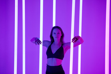 Skinny fashion model wear black erotic lingerie in colorful bright neon uv purple lights posing in studio. Close up.