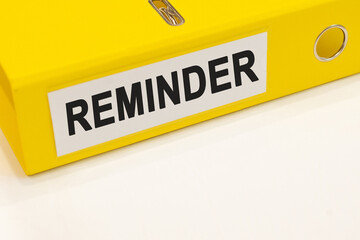 The word reminder on a white background with a yellow folder. Business concept