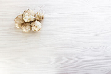 Fototapeta na wymiar ginger root lies on a beige wooden background Jerusalem artichoke root