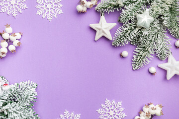 Christmas holidays composition with white christmas decorations and fir tree branches on purple background with copy space, top view