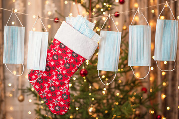 Creative garland made of medical masks and christmas sock, fir-tree on the background. Winter time...