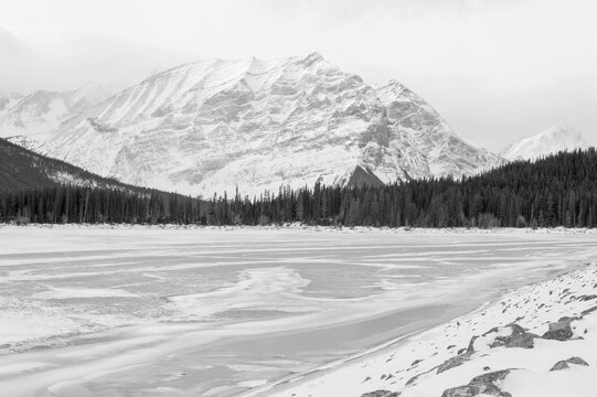 winter landscape with snow covered lake in front of majestic mountain done in black and white photograph 