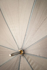 Beige / brown / gray umbrella center with small rain drops on the fabric 