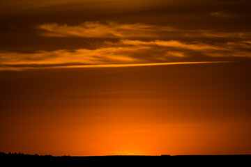 Fototapeta premium PUESTA DE SOL CON CIELO NARANJA ILUMINADO POR EL SOL