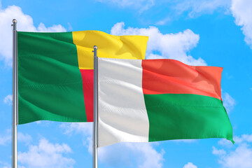 Obraz premium Madagascar and Benin national flag waving in the windy deep blue sky. Diplomacy and international relations concept.