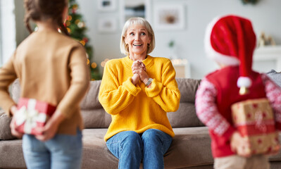 happy family grandchildren gives a cheerful smiling grandmother a Christmas gift.