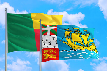 Saint Pierre And Miquelon and Benin national flag waving in the windy deep blue sky. Diplomacy and international relations concept.