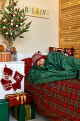 Little kid sleeping next to Christmas tree