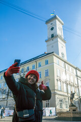 woman taking selfie on her phone lviv city hall on background