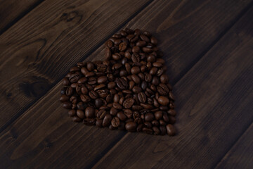 Heart of coffee beans on dark wooden table