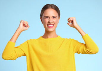 happy expressive young woman  shouts celebrating victory success and triumph on  blue background.