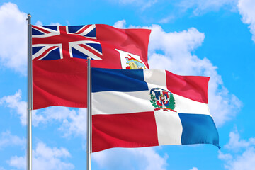 Dominican Republic and Bermuda national flag waving in the windy deep blue sky. Diplomacy and international relations concept.