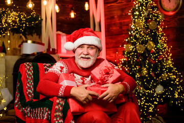 Obraz na płótnie Canvas Santa Claus relaxing in arm chair. Delivering gifts. Winter vacation. Merry christmas. Elderly grandpa at home. Traditions concept. Santa Claus near christmas tree. Bearded senior man Santa Claus
