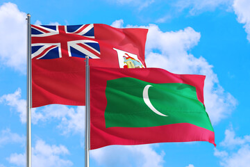 Maldives and Bermuda national flag waving in the windy deep blue sky. Diplomacy and international relations concept.