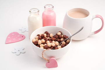 Healthy Breakfast with cereal balls and milk drinks and pink hearts on a light background. Side view. Concept of holiday backgrounds.