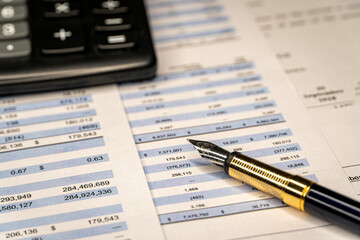 Fototapeta premium Calculator and pen with accounting report and financial statement on desk. Accounting business plan concept.