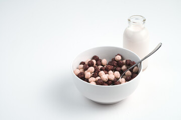 Round wheat flakes in a plate and milk in a bottle on a white background. Grocery background. The concept of proper nutrition.