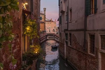 Naklejka na ściany i meble View at sunset of a small and picturesque Venice canal crossed by a bridge. Concept: Venetian atmosphere