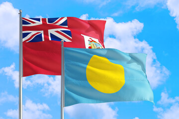 Palau and Bermuda national flag waving in the windy deep blue sky. Diplomacy and international relations concept.