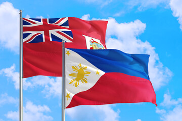 Philippines and Bermuda national flag waving in the windy deep blue sky. Diplomacy and international relations concept.