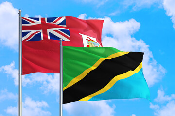 Tanzania and Bermuda national flag waving in the windy deep blue sky. Diplomacy and international relations concept.