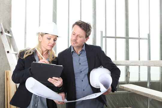 Man And Woman Architects Or Engineers Work Together Discussing With Blueprint In The Inside The Construction Building Site