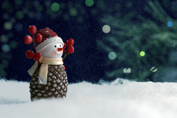 A snowman stands near the Christmas tree. Snow is falling.