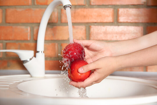 Woman washing fresh nectarines in kitchen sink, closeup