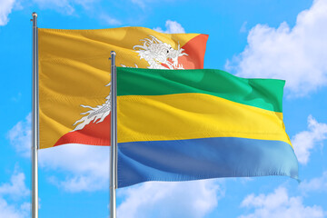 Gabon and Bhutan national flag waving in the windy deep blue sky. Diplomacy and international relations concept.