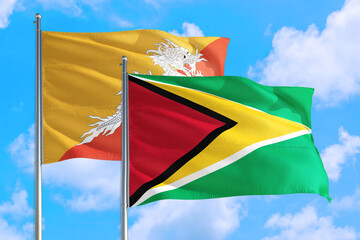 Guyana and Bhutan national flag waving in the windy deep blue sky. Diplomacy and international relations concept.