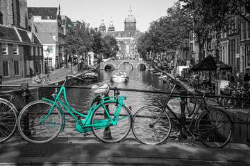 Fototapeta premium An azure bike on the streets of Amsterdam. Symbol for clean and ecological urban transport. Isolated in a black and white background. 