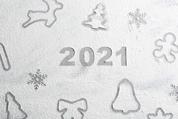 Different Christmas cookie shapes and number 2021 made of flour on grey table, top view
