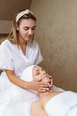 Fototapeta na wymiar Face massage. Close-up of adult woman getting spa massage treatment at beauty spa salon. Spa skin and body care. Facial beauty treatment. Cosmetology.