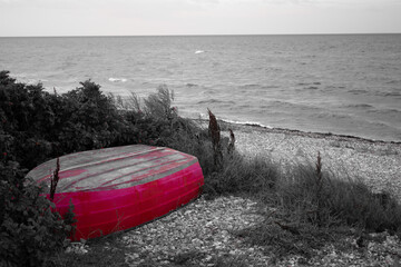 Overturned abandoned boat on beach of calm Northen sea