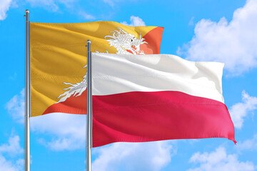 Poland and Bhutan national flag waving in the windy deep blue sky. Diplomacy and international relations concept.