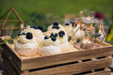 Mini pavlovas with mascarpone filling and berries on sweet table buffet at a relaxed, rustic...