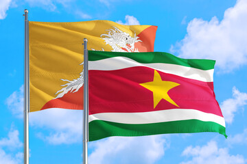 Suriname and Bhutan national flag waving in the windy deep blue sky. Diplomacy and international relations concept.