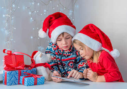 Online christmas greetings. Brother and sister in Santa hats call grandparents.