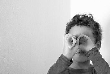 boy looking through paper roll on white background stock photo