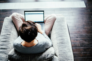 A woman works on a computer from home. Work from home in a comfortable chair, top view