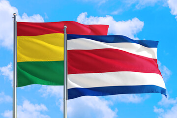 Costa Rica and Bolivia national flag waving in the windy deep blue sky. Diplomacy and international relations concept.