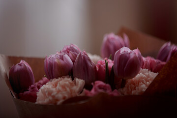 Bouquet of beautiful flowers with purple peony roses, carnations and tulips, in the craft paper