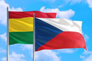 Fototapeta na wymiar Czech Republic and Bolivia national flag waving in the windy deep blue sky. Diplomacy and international relations concept.
