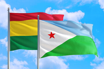 Djibouti and Bolivia national flag waving in the windy deep blue sky. Diplomacy and international relations concept.