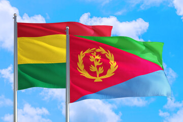 Eritrea and Bolivia national flag waving in the windy deep blue sky. Diplomacy and international relations concept.