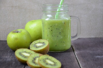 Green healthy smoothie in glass jar: banana, kiwi, green apple on rustic background