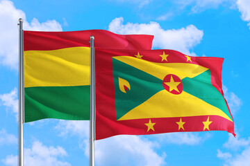 Grenada and Bolivia national flag waving in the windy deep blue sky. Diplomacy and international relations concept.